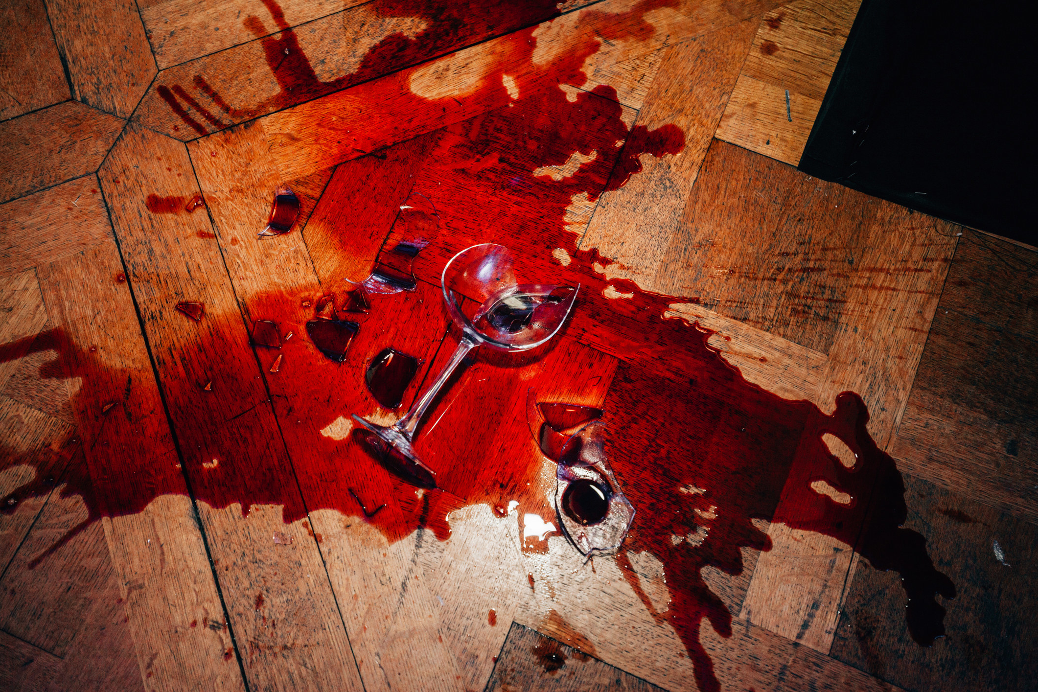 A broken red wine glass on the floor