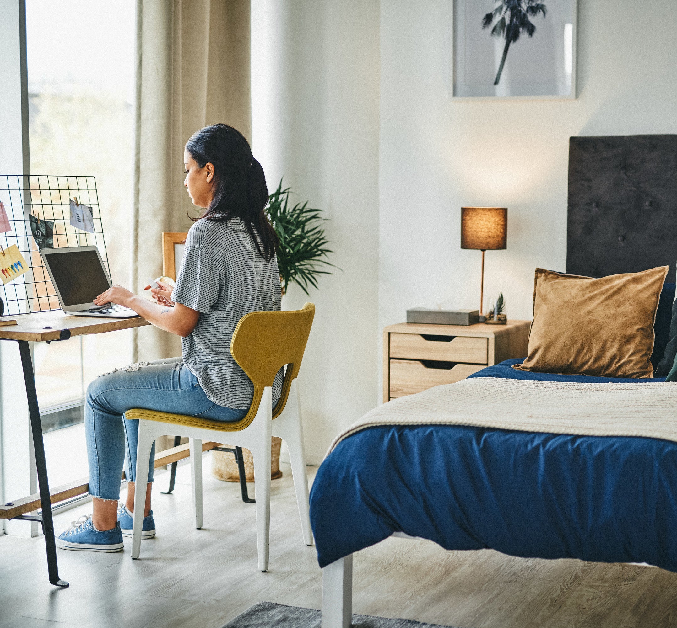 Woman working on laptop on desk in her bedroom