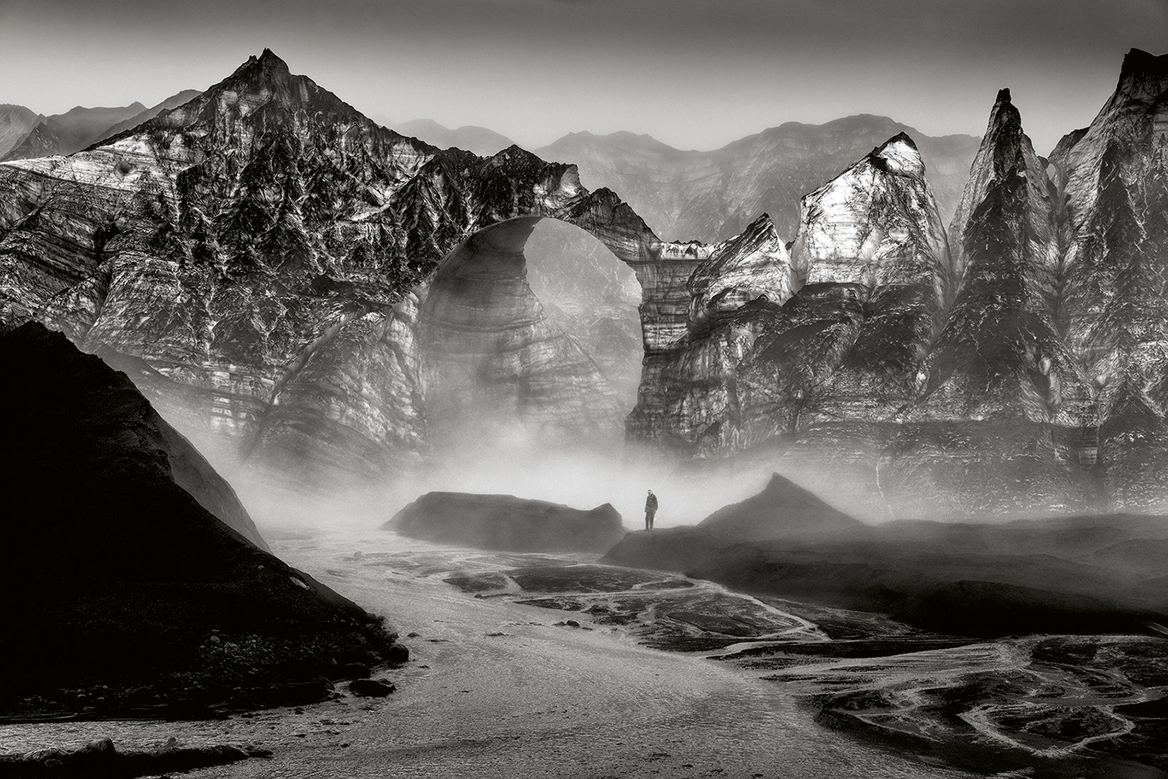A person seen in the distance with rock formations and fog