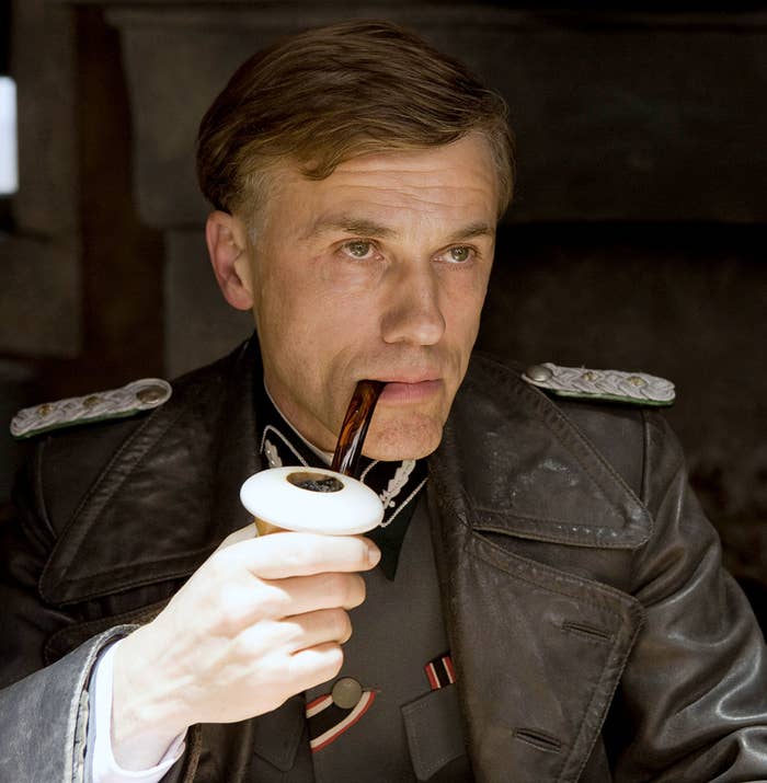 Christoph Waltz as Landa, smoking a giant pipe wearing a leather coat