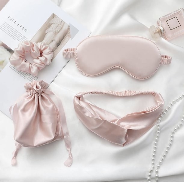 A pink silky eye mask, scrunchie, headband, and pouch