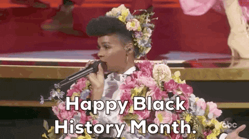 Janelle Monae in a floral outfit at the Oscars saying &quot;Happy Black History Month&quot; into the microphone
