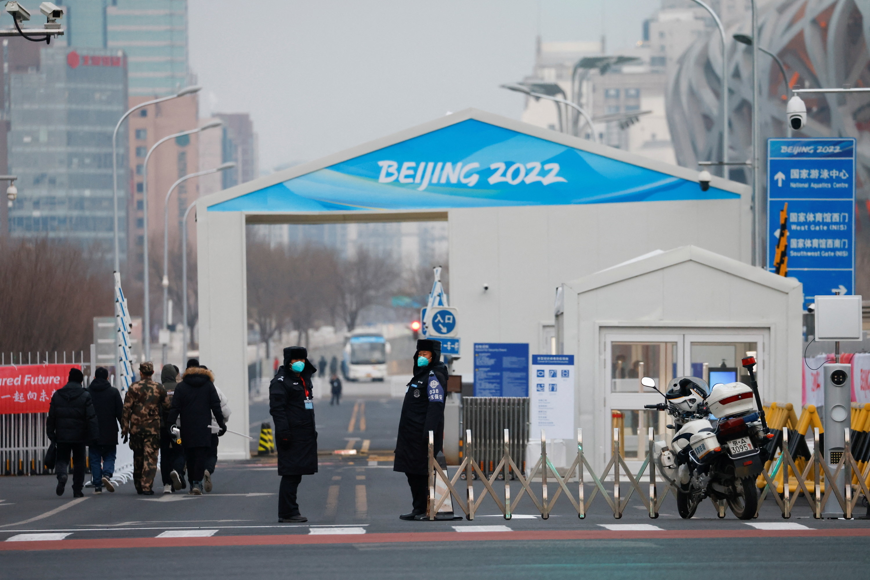 Security personnel, wearing blue masks, stand outside an entrance to the Closed Loop &quot;bubble&quot; area created to prevent the spread of COVID-19 near the National Stadium