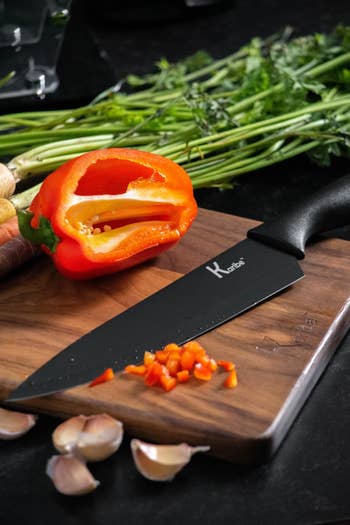 a black knife being used to slice a pepper
