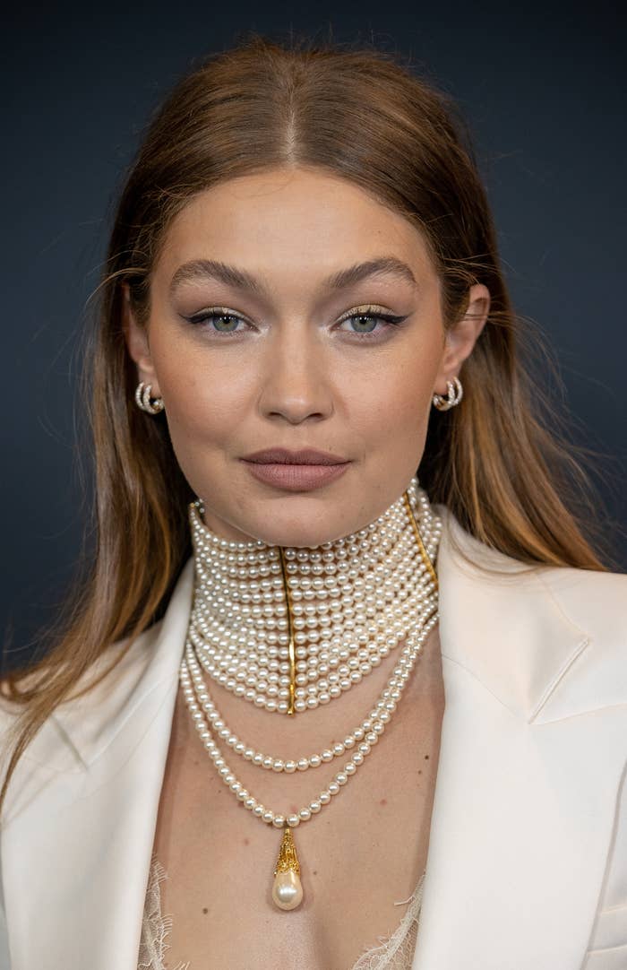 A closeup of Gigi wearing a large pearl necklace