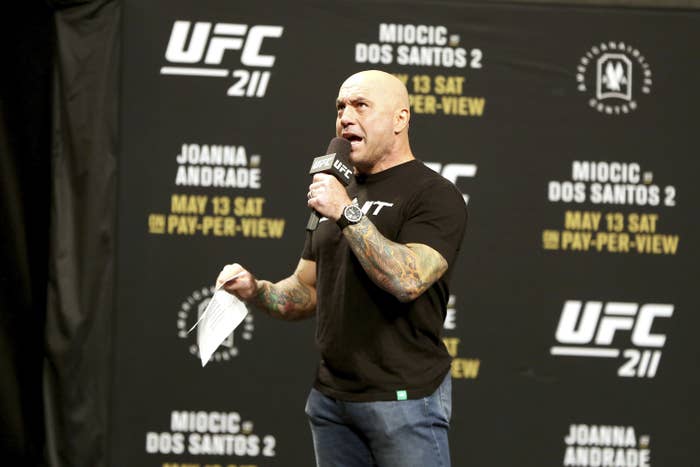 Rogan standing and speaking into a UFC microphone