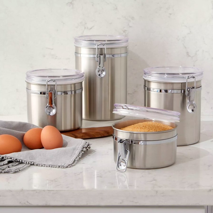 Stainless steel canisters on a marble counter next to a dish towel with eggs