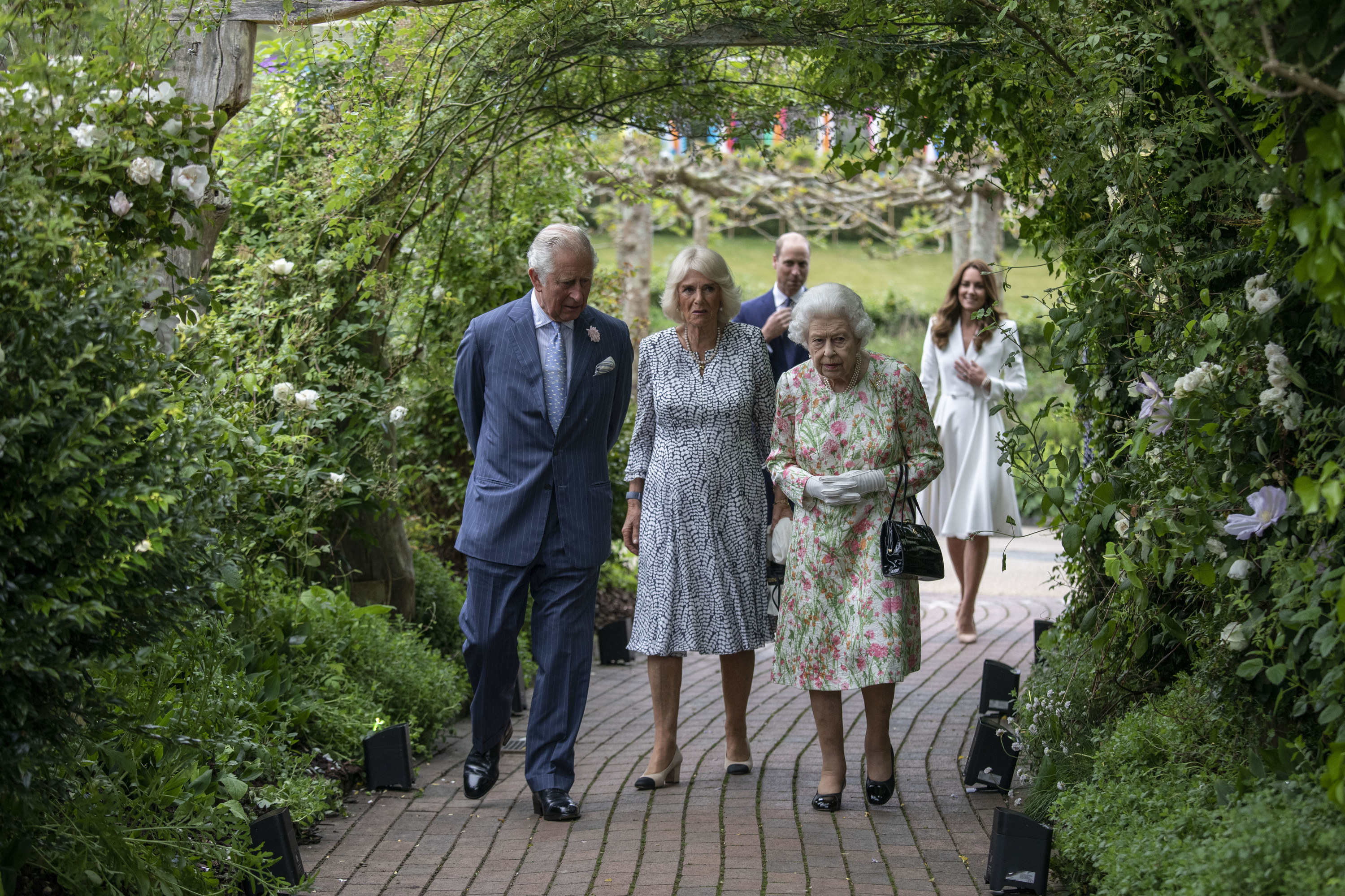 The trio walk along a treelined path with Prince William and Catherine, Duchess of Cambridge, behind them 