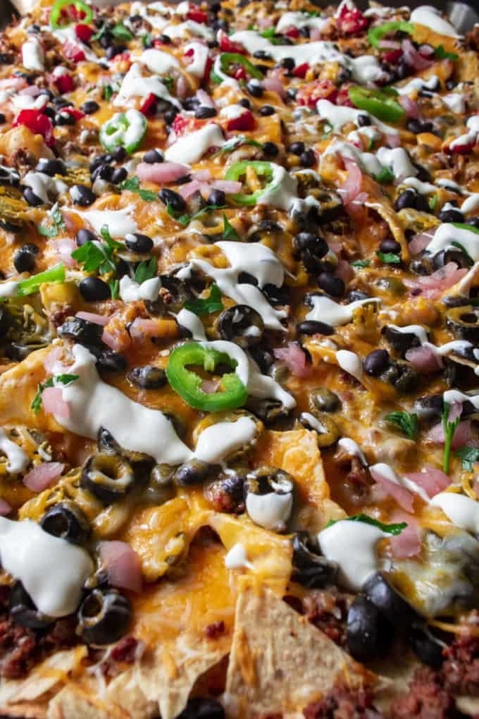 Nachos topped with beef, pickled onions, olives, cheese, sour cream, and more.