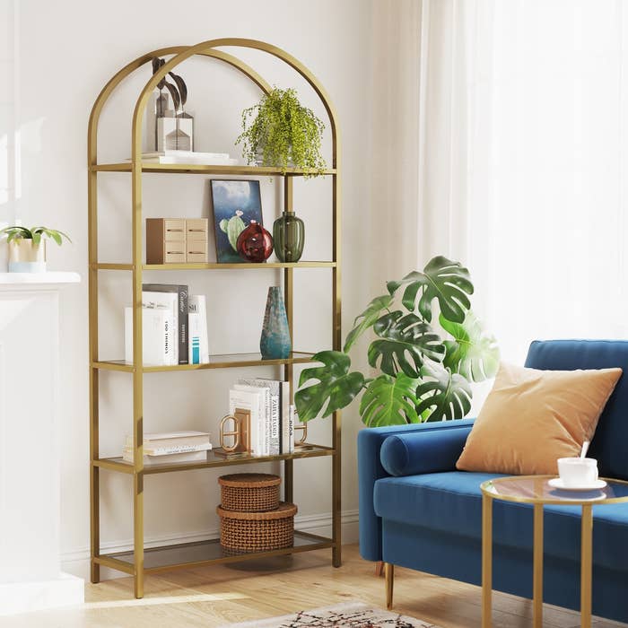 A gold bookcase with a rounded top in a living room.