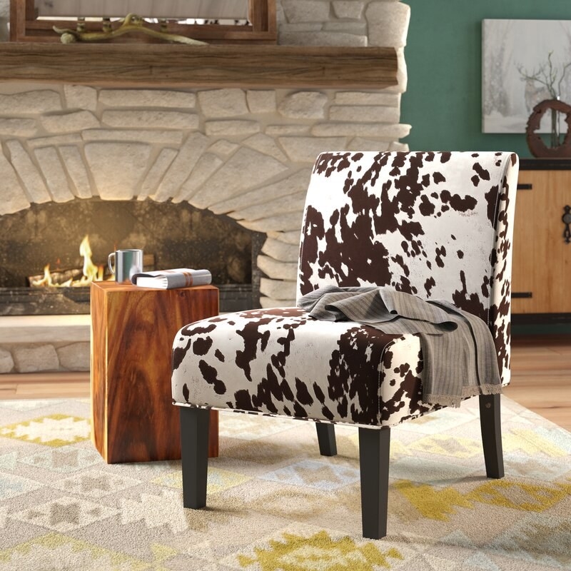 A cow hide couch in a cozy living room with a fire burning in the background.