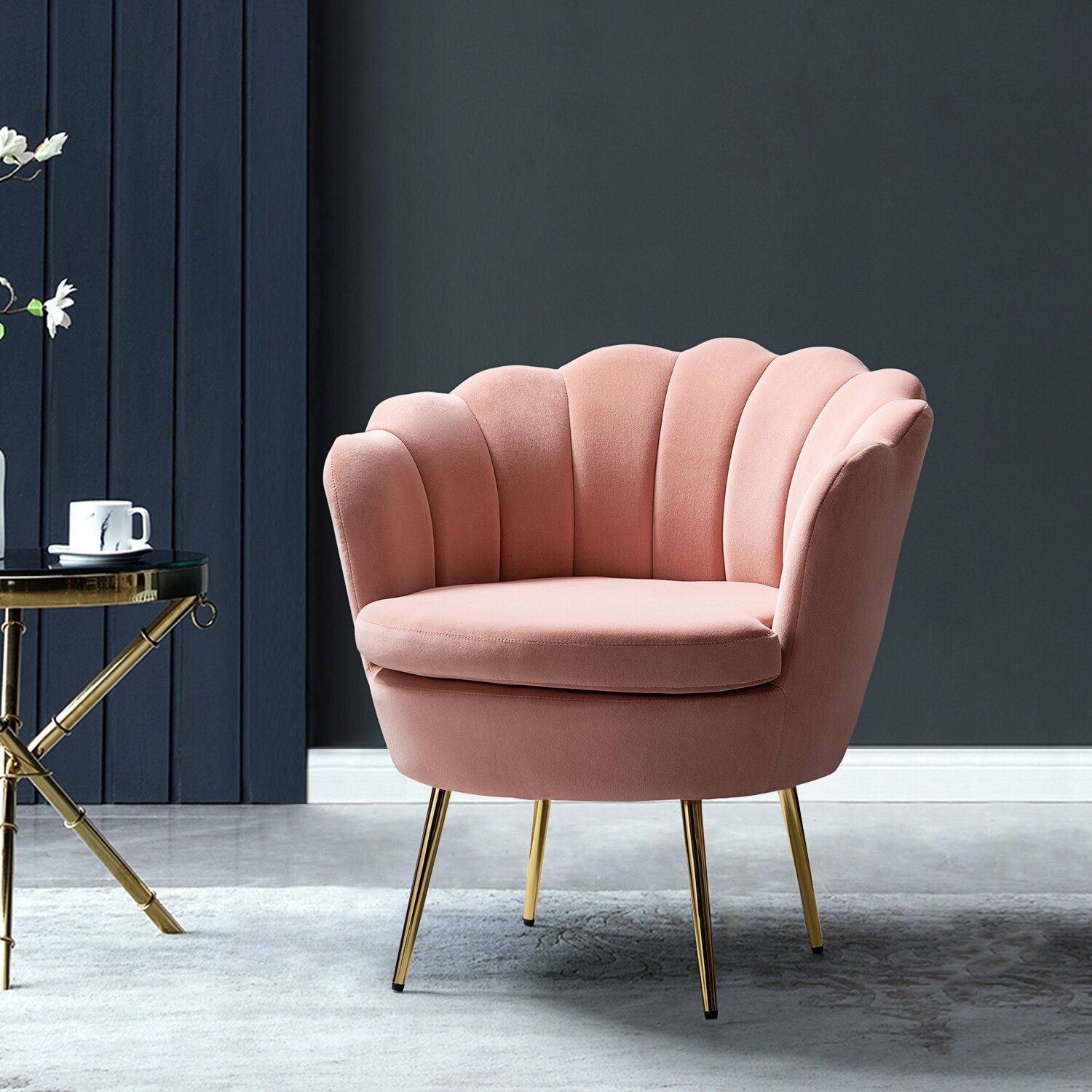 A light pink velvet accent chair that has a shell-like cushion.