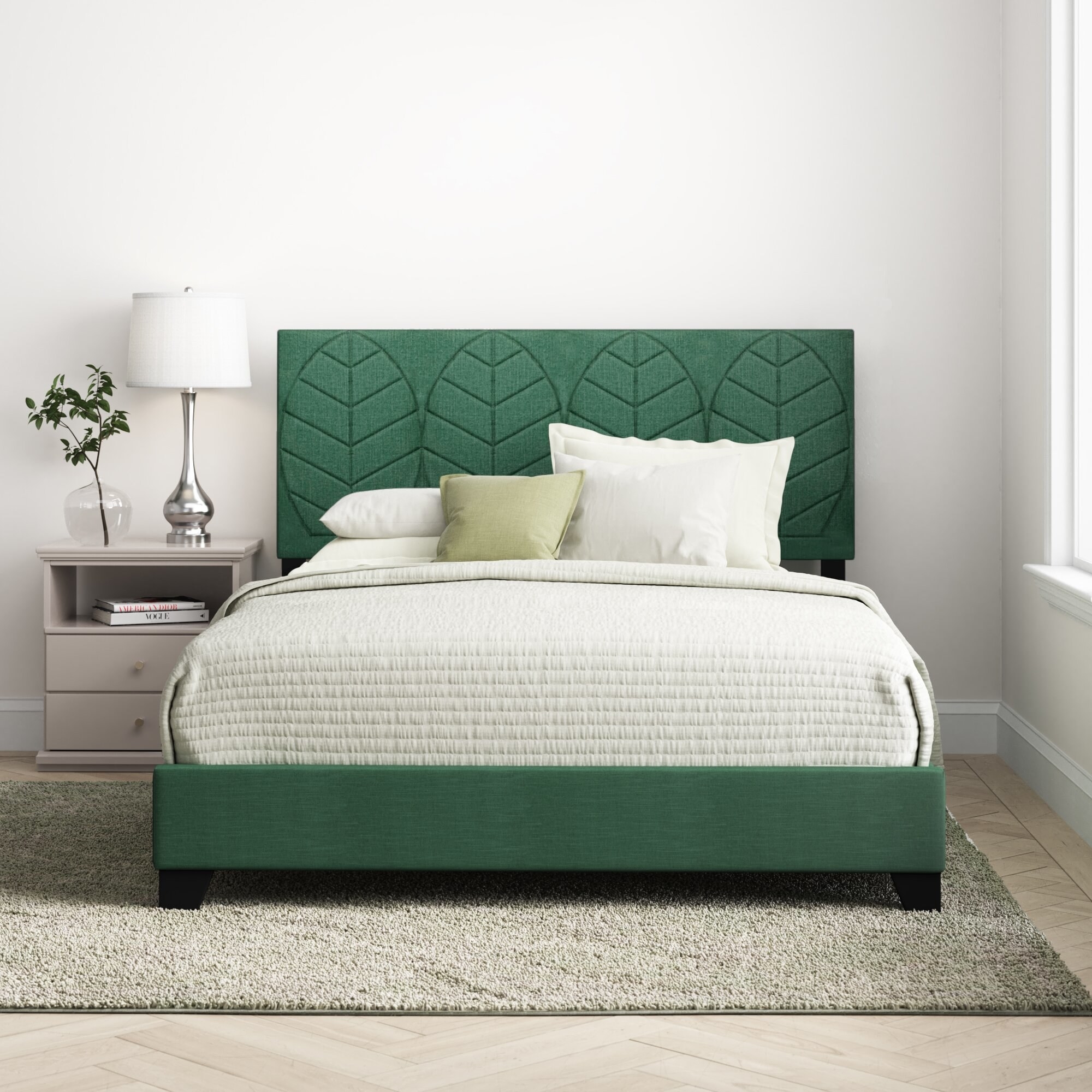 A green bed with a leaf pattern on the headboard in a bedroom.