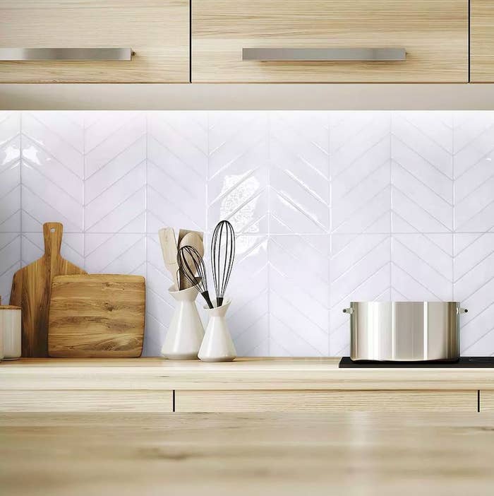 White tile backsplash shown behind kitchen countertops filled with kitchen accessories