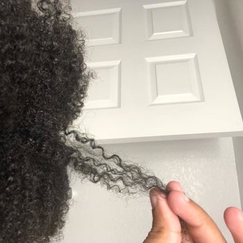 reviewer with 4c hair holding a section of their hair showing how strong and moisturized it looks