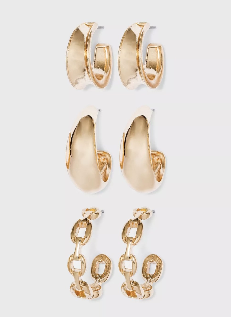 There are three pairs of gold earrings — two solid chunky hoops and one pair of chain hoops