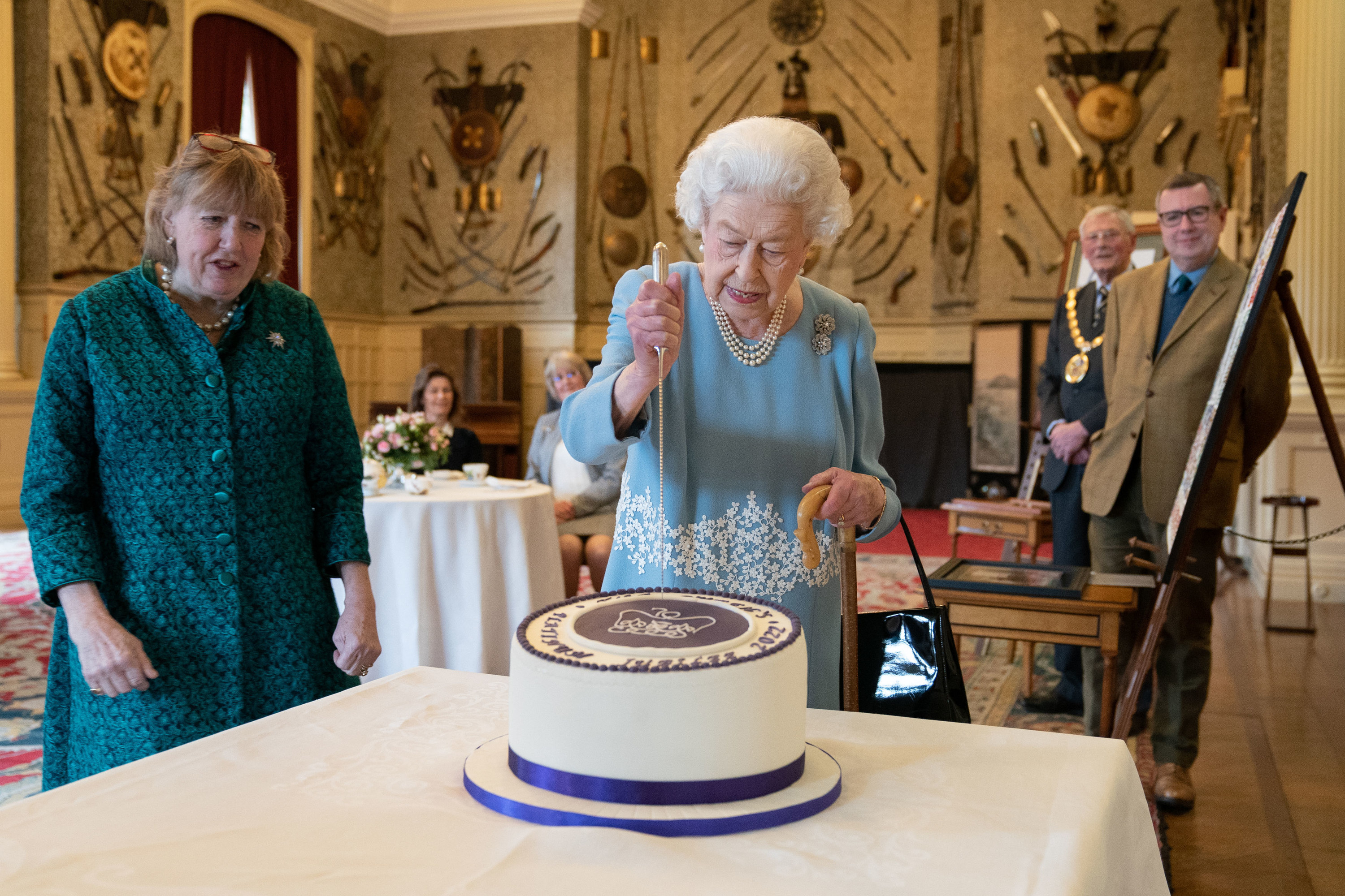 Queen Elizabeth II  preparing to stab a jubilee cake 