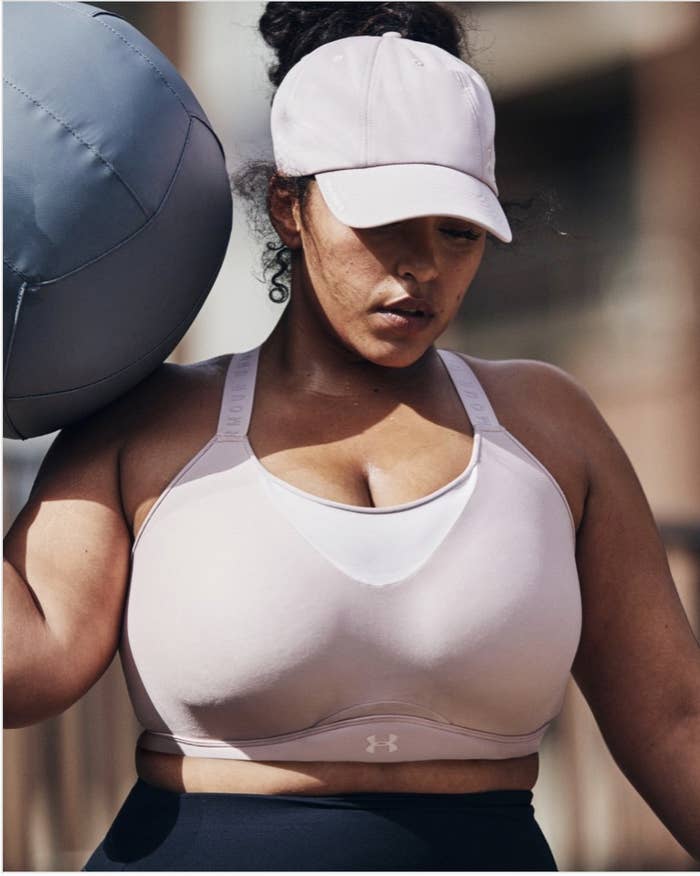 A person wearing the sports bra while carrying a medicine ball during a workout