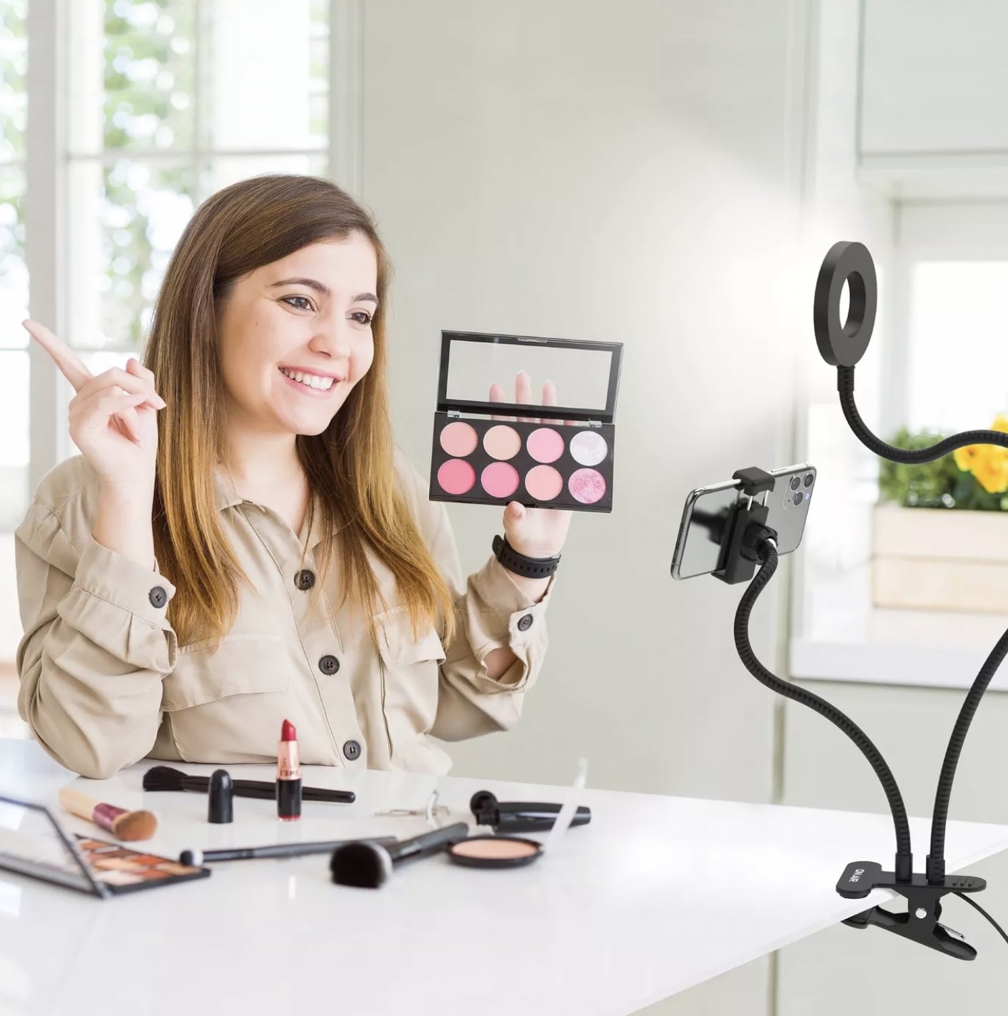 A model filming a make-up tutorial with her phone being held by the stand and ring light providing ideal selfie lighting