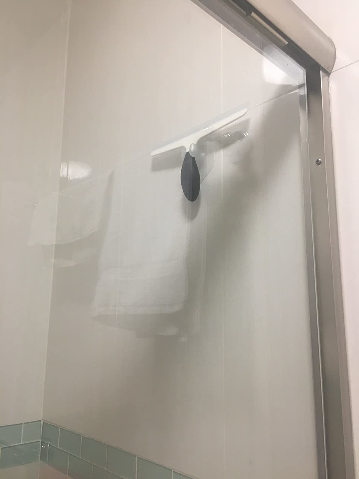 the squeegee hanging on a shower wall