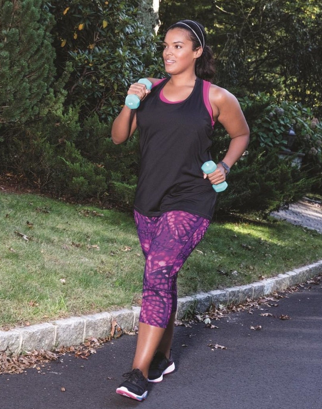 A person wearing the leggings in a bold pattern while taking a walk with weights outside
