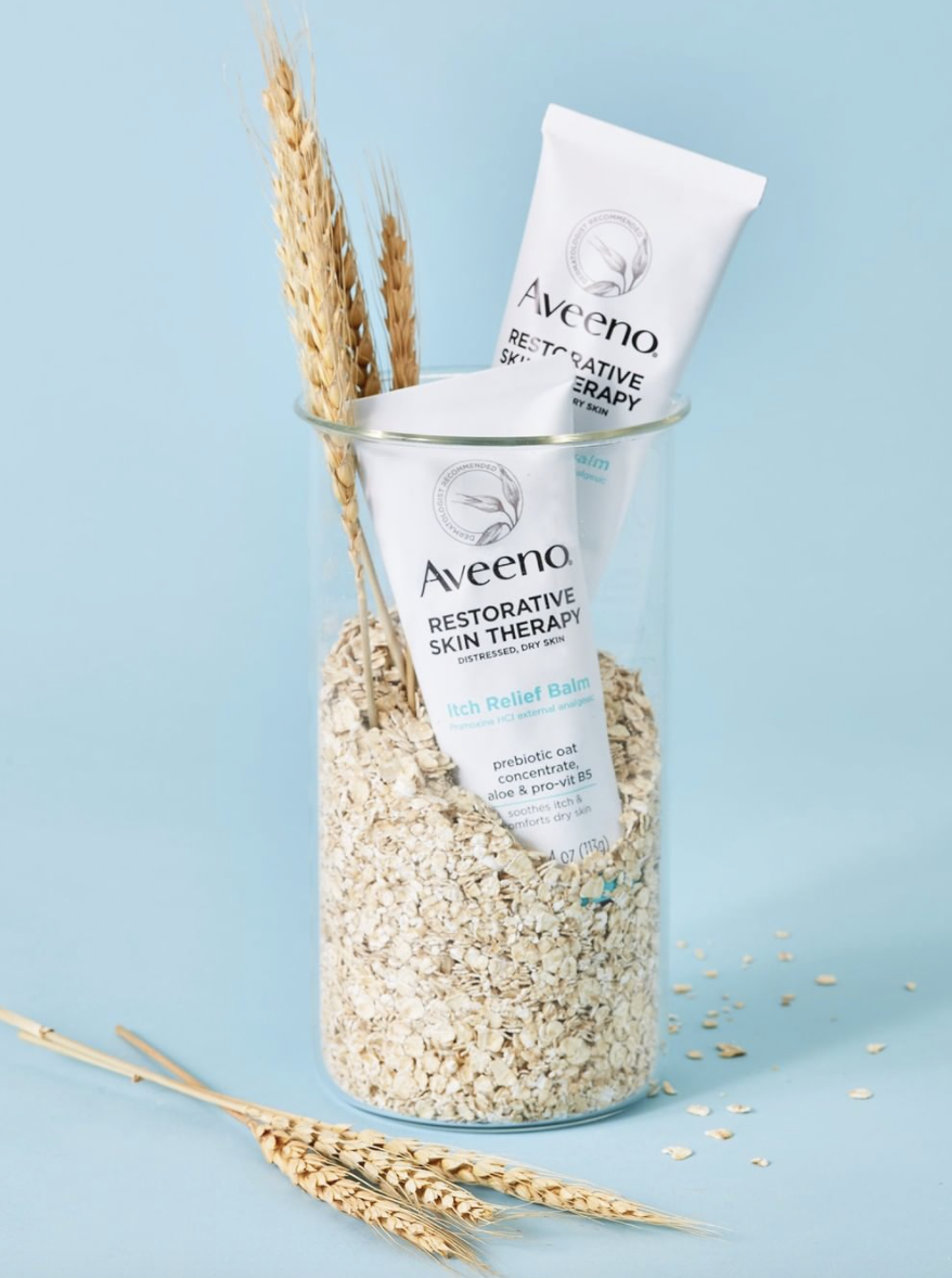 Two tubes of itch relief balm in a glass vase with oats in it