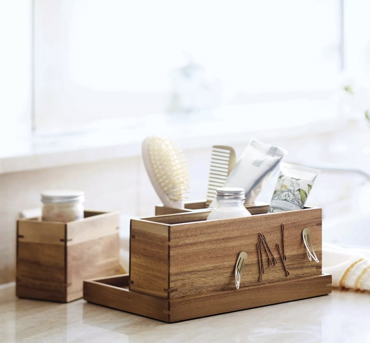 The wooden organizer with three separate sections filled with bathroom accessories and bobby pins and hair clips attached on the magnetic part of the wood