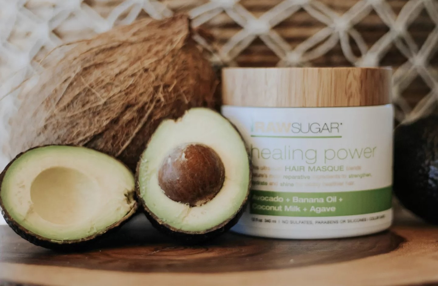 The jar of healing hair masque next to a sliced avocado