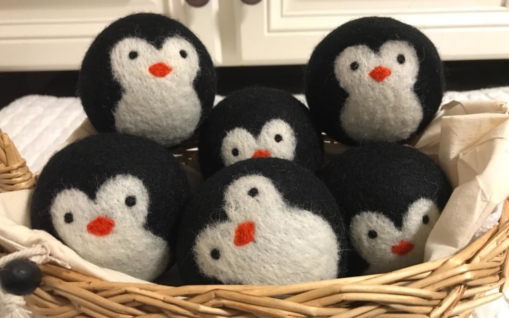 a reviewer photo of the black and white dryer balls designed to look like penguins piled into a basket