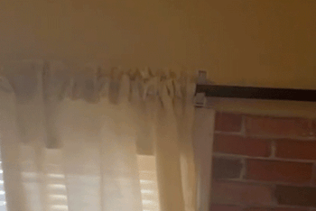 GIF of reviewer showing their curtain rods installed with the broom holders