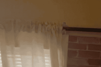 GIF of reviewer showing their curtain rods installed with the broom holders