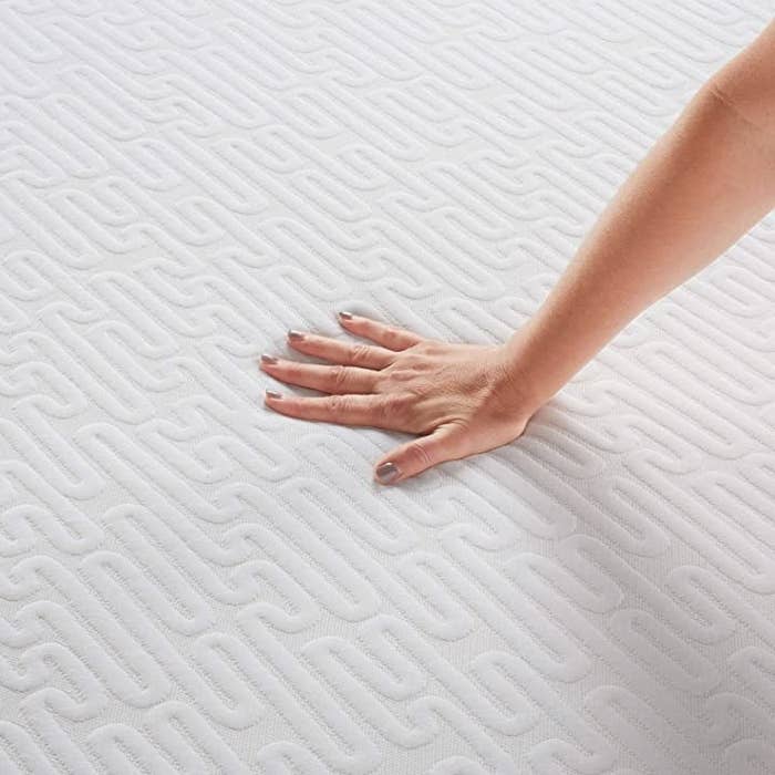 Woman pressing hand into white Serta memory foam mattress