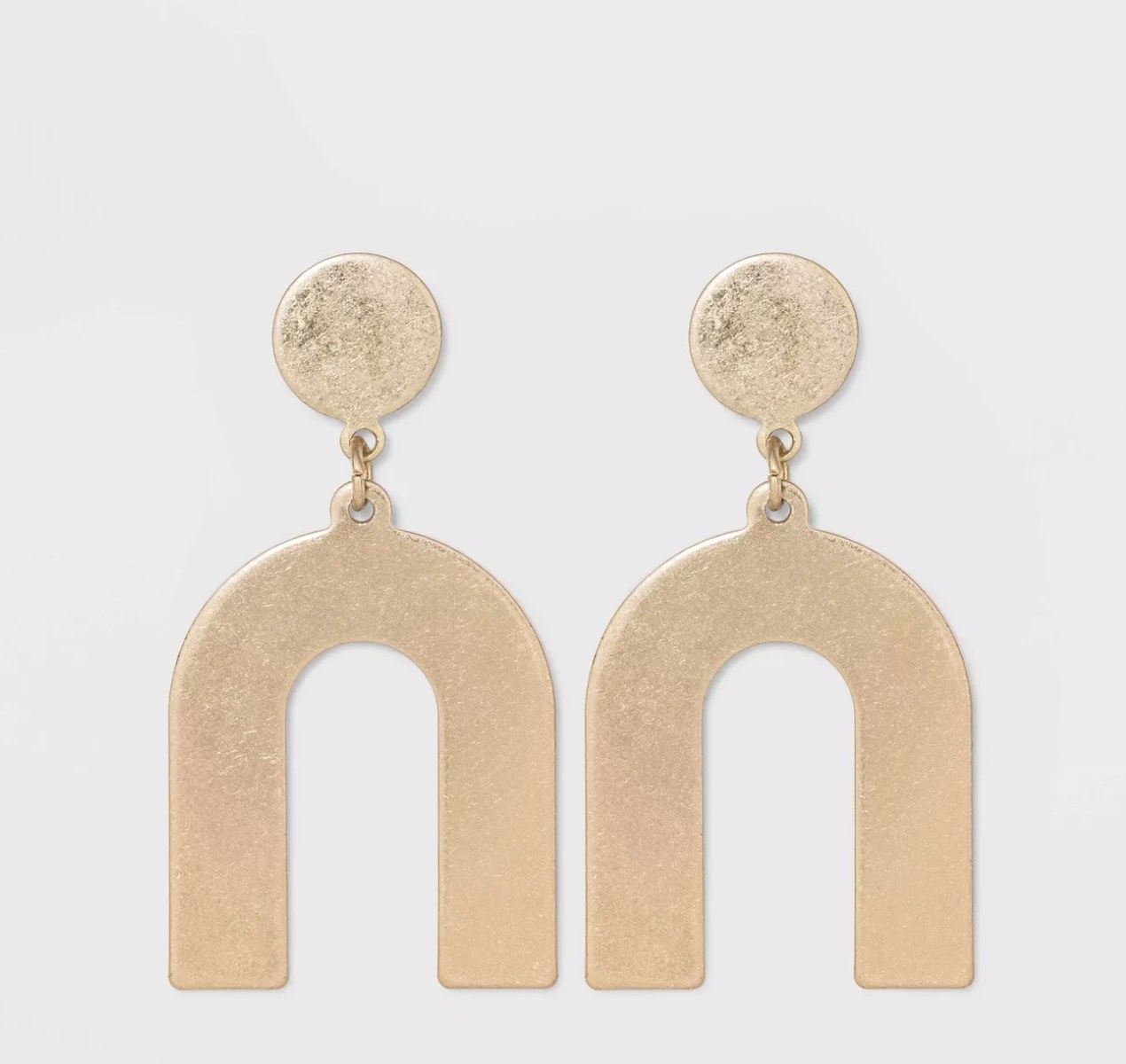 The gold earrings have a circular base and an upside down U-shape connected to them