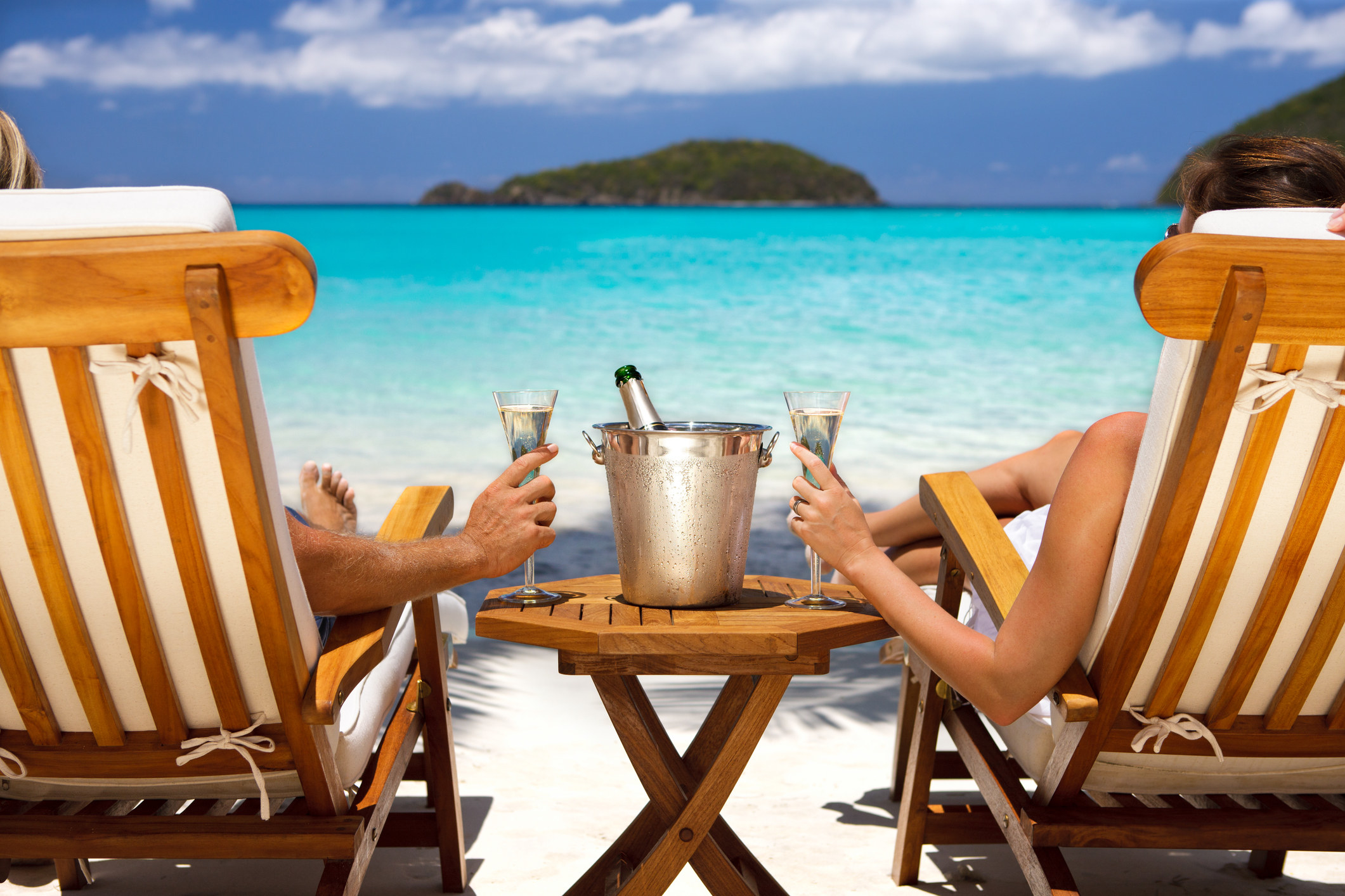 A couple relaxes in chairs on the beach outside at a luxury resort
