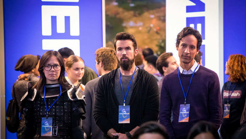 Rob McElhenney and Danny Pudi stand at a video game convention