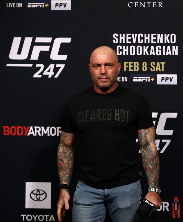 Rogan poses for a photo while holding a microphone at a UFC event