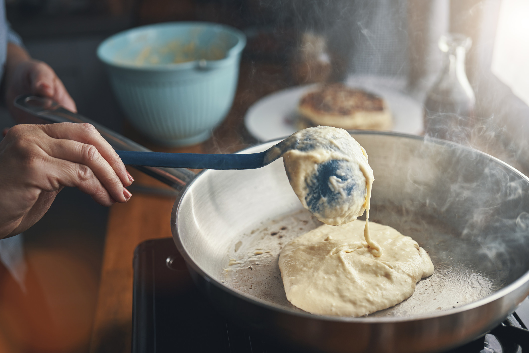 A person making pancakes in a skillet.
