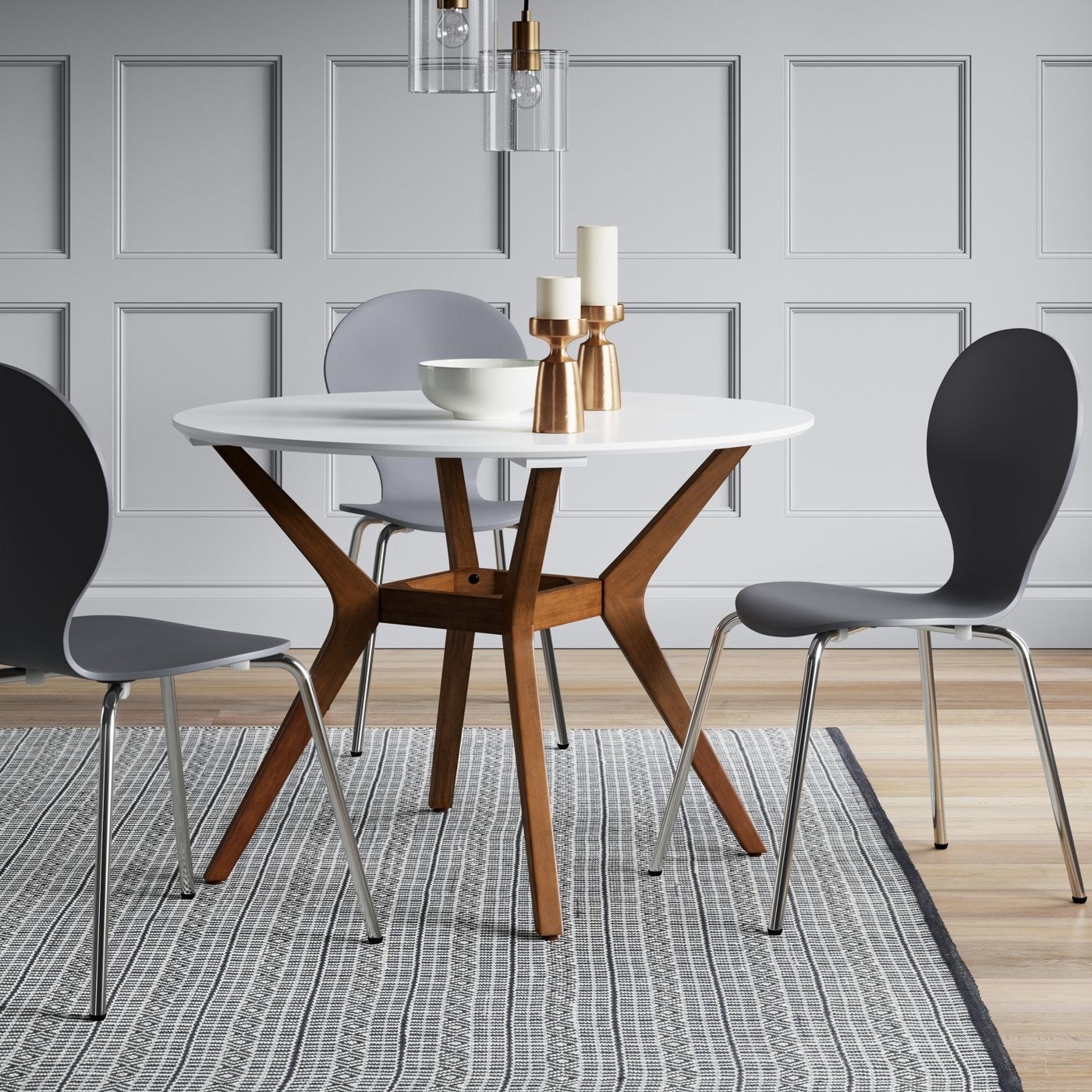 round dining table with white top and wood legs, next to black chairs