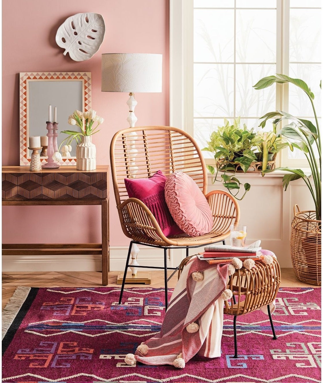 rattan arm chair with pink pillows on top next to a matching ottoman