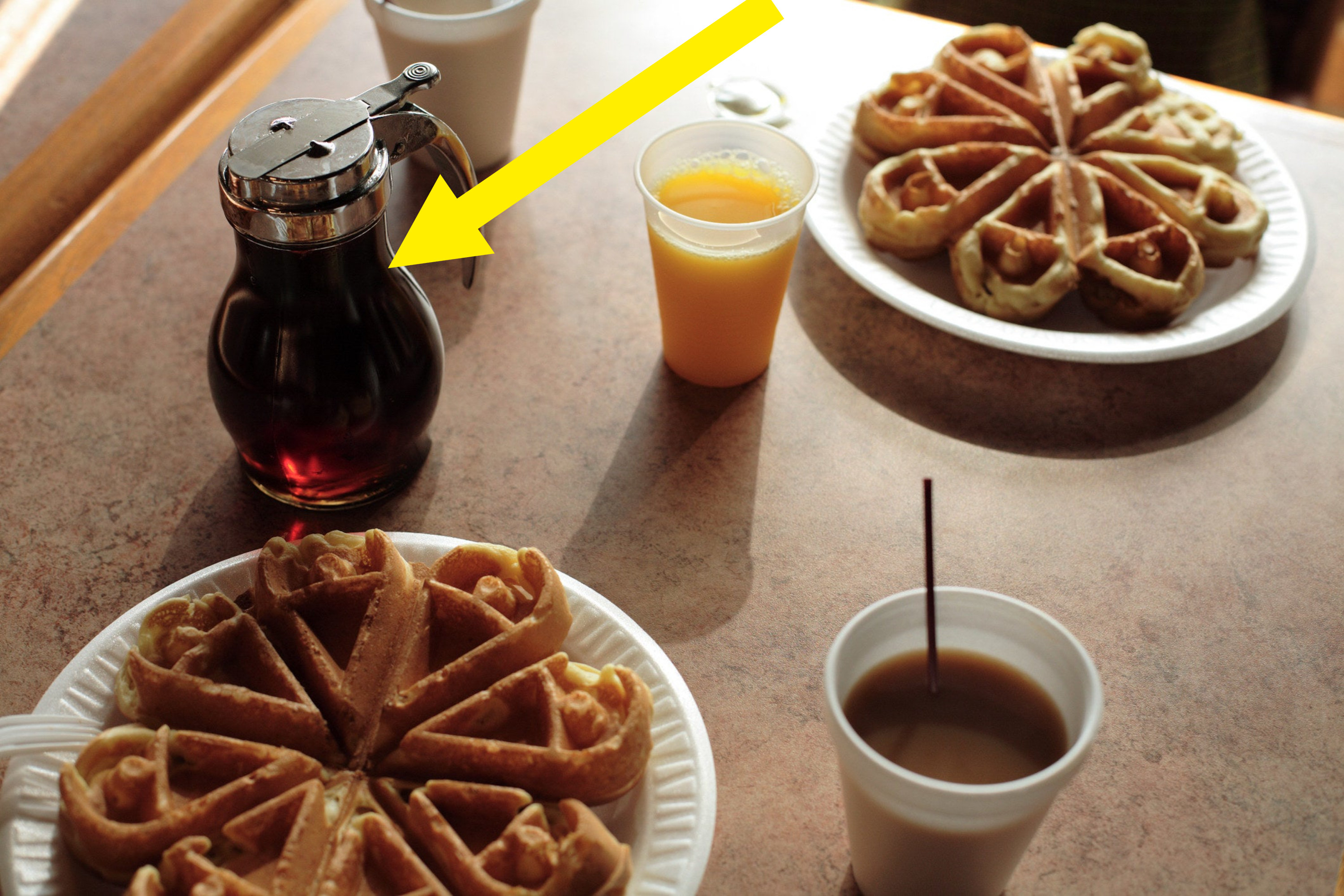 American breakfast in diner with waffles, orange juice, and syrup