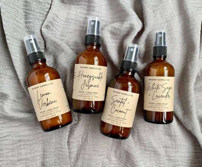 four brown spray bottles in different scents: lemon verbena, honeysuckle jasmine, santal and coconut, and white sage and lavender