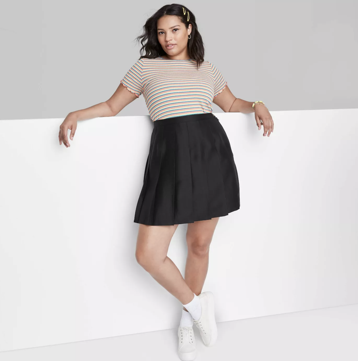model wearing the skirt in black with a striped top and white sneakers
