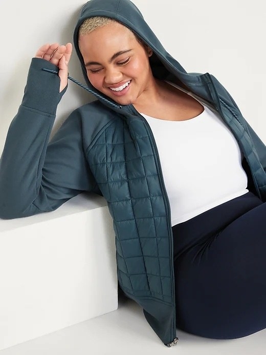 A person wearing the coat sitting against a block with their right arm propped up on it