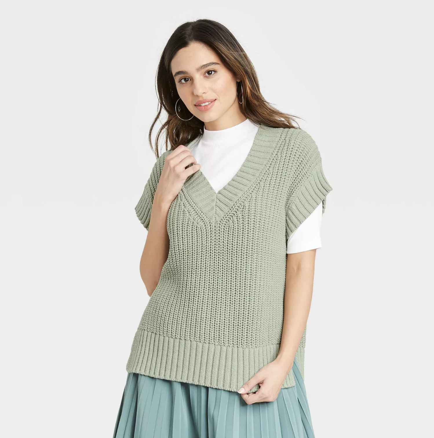 model wearing the sweater vest in green over a white shirt