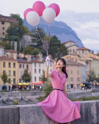 model wearing the pink dress while holding balloons