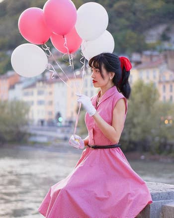 close up of model wearing the pink dress while holding balloons