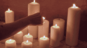 a woman lights a bunch of candles