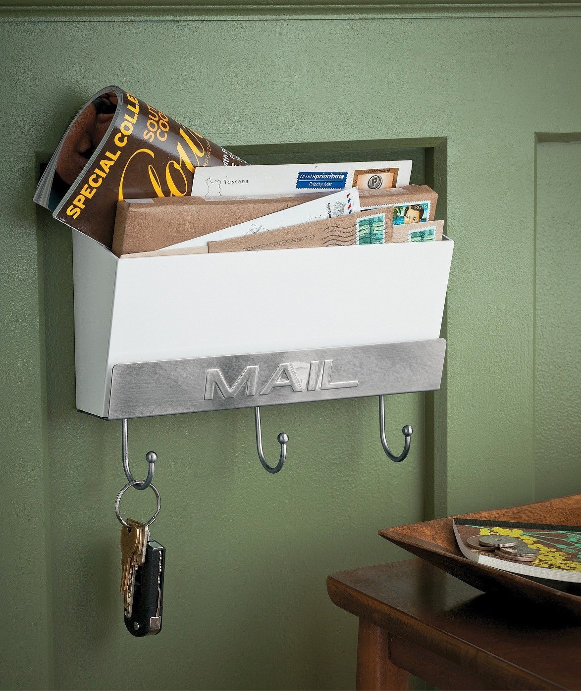 The mail holder hangs on a green wall with letters and keys
