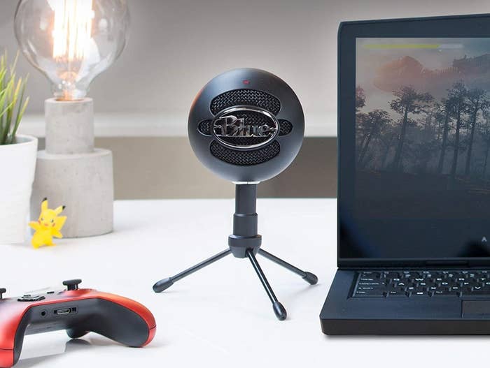 The microphone on a desk next to an open laptop and video game controller