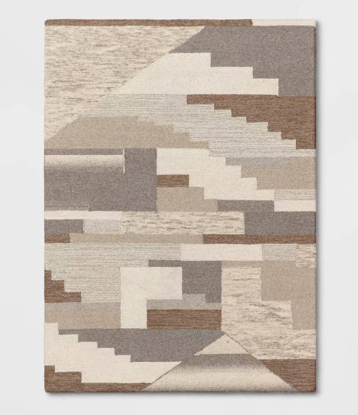 The tufted area rug has tone of brown, creme, grey and tan in geometric shapes